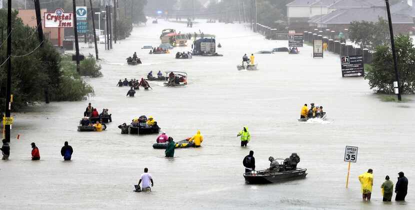 In this Aug. 28, 2017, photo, rescue boats fill a flooded street as flood victims are...
