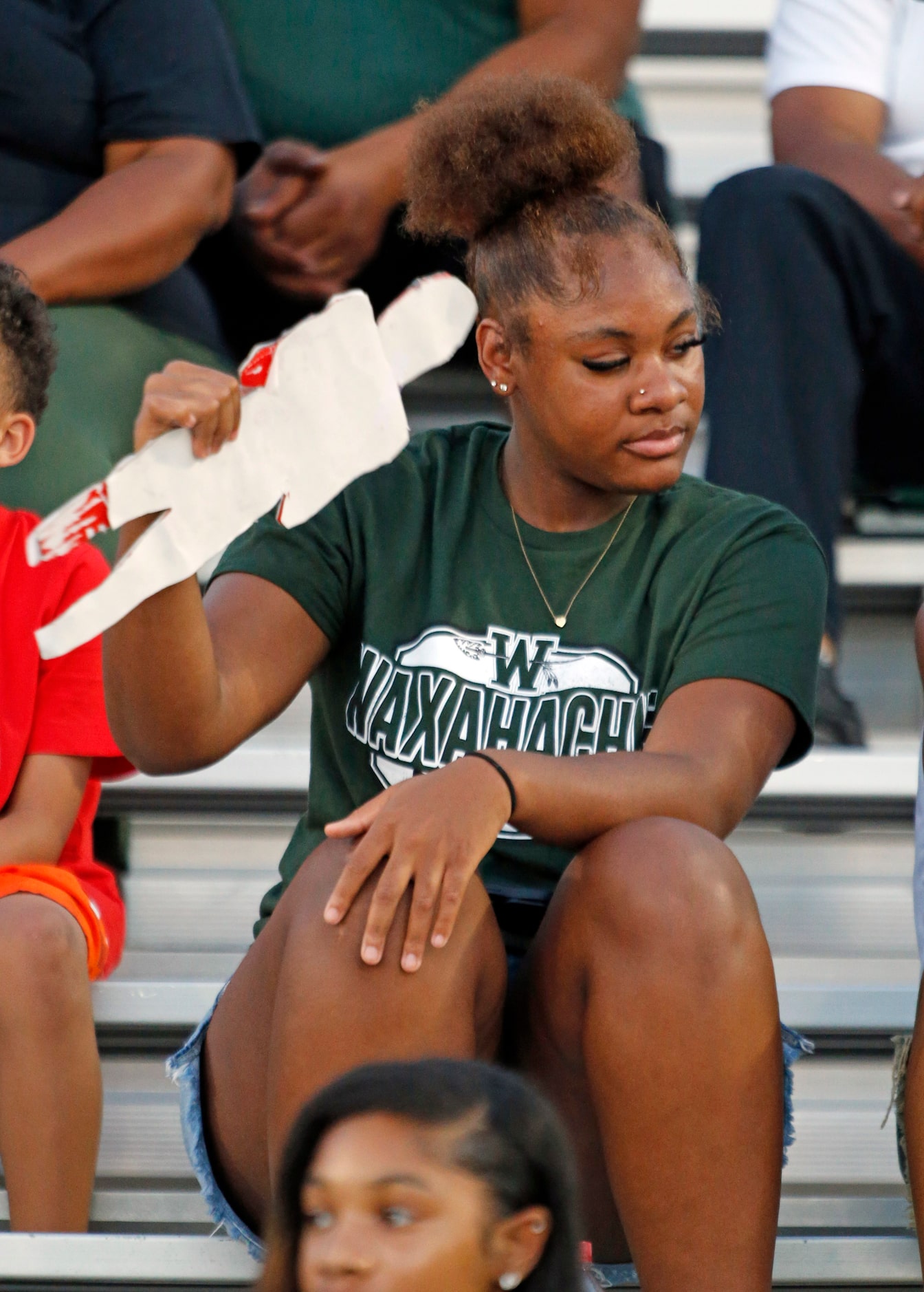 A Waxahachie fan fans herself with a cardboard football silhoutte before the first half of a...