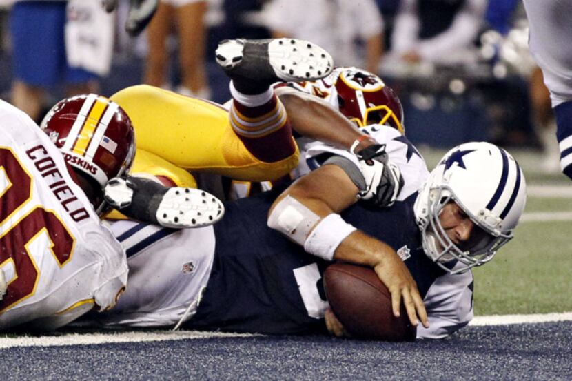Dallas Cowboys quarterback Tony Romo (9) dives past Washington Redskins defenders to score a...