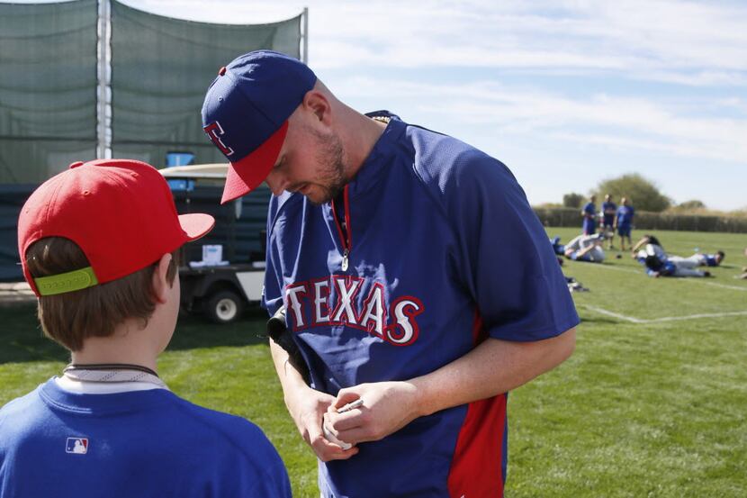 Texas pitcher Matt Harrison signs an autograph during Texas Rangers baseball spring training...