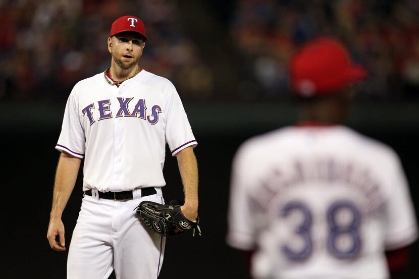 Texas Rangers starting pitcher Scott Feldman sits in the dugout after being pulled from the...