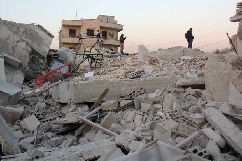 Syrian men stand amidst the rubble of a building following a reported airstrike by...