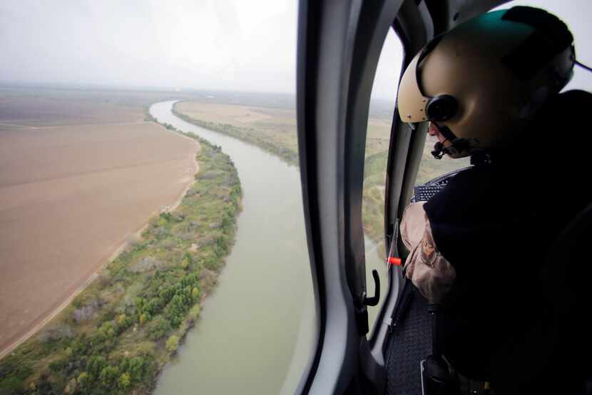 In this aerial photo, a U.S. Customs and Border Protection Air and Marine agent looks out...