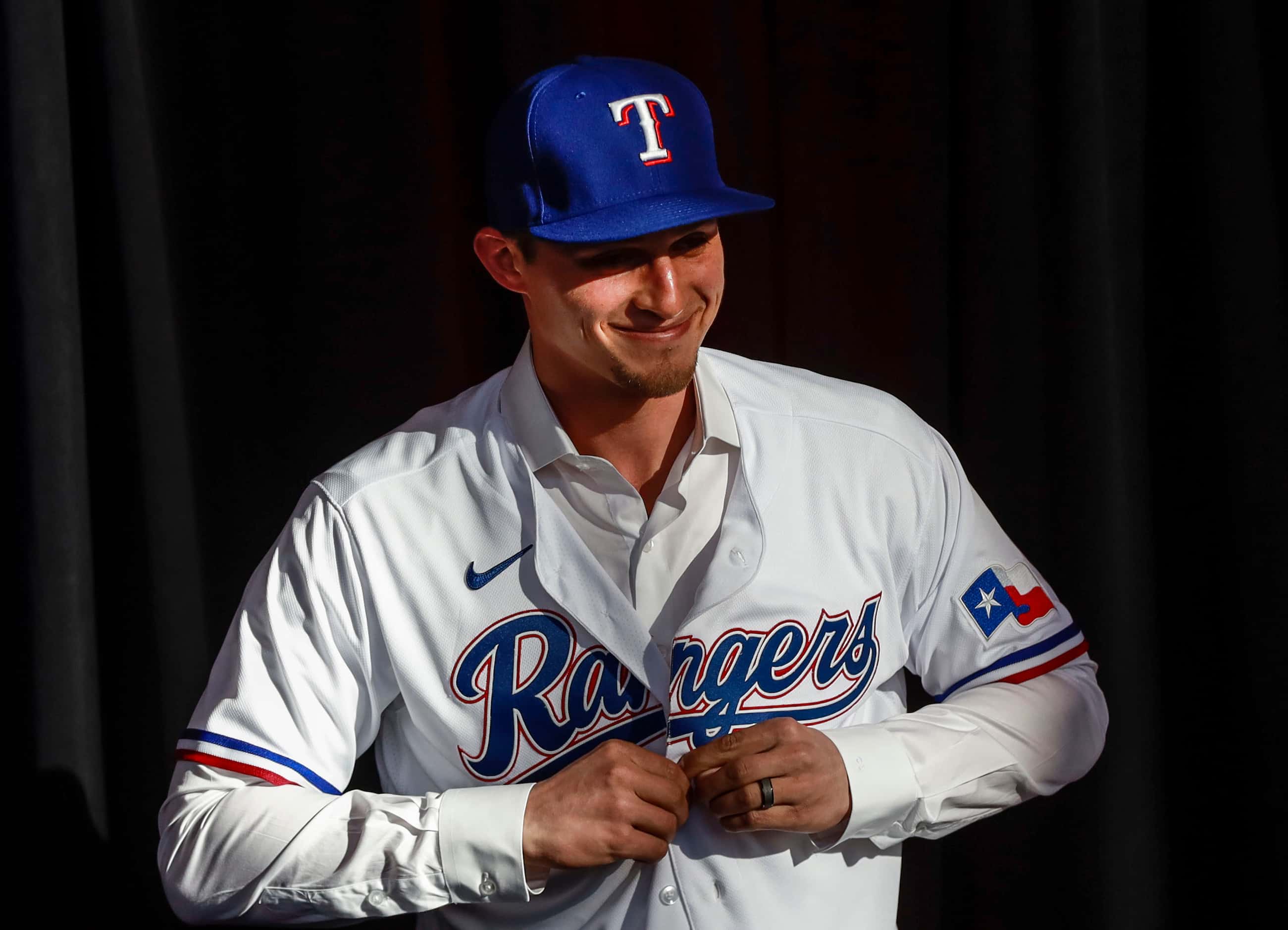 Corey Seager puts on his jersey at a news conference at Globe Life Park in Arlington on...