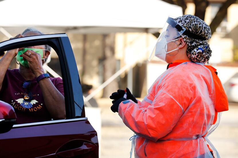Medical assistant Jessica Williams watches as a driver takes a self-administered COVID-19...