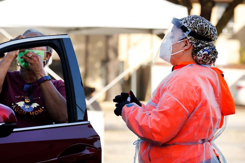 Medical assistant Jessica Williams watches as a driver takes a self-administered COVID-19...