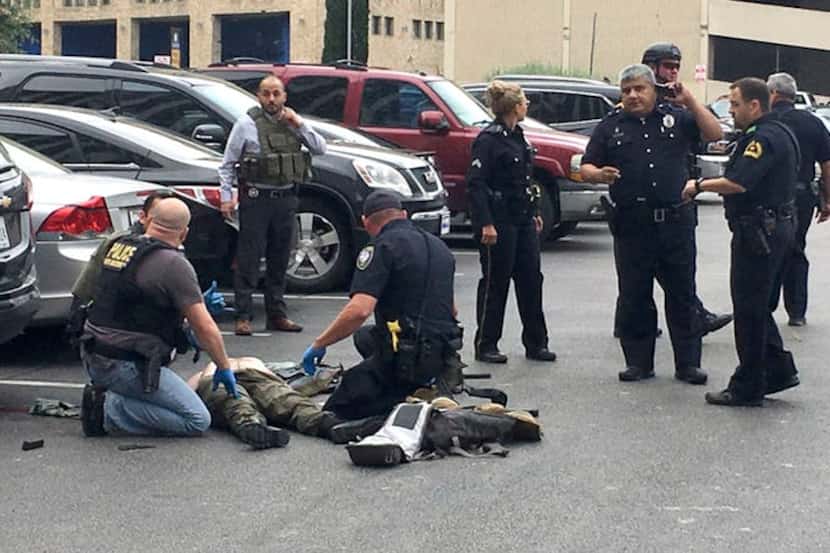 Los oficiales de policía atienden a un hombre al que derribaron después de que disparó al...