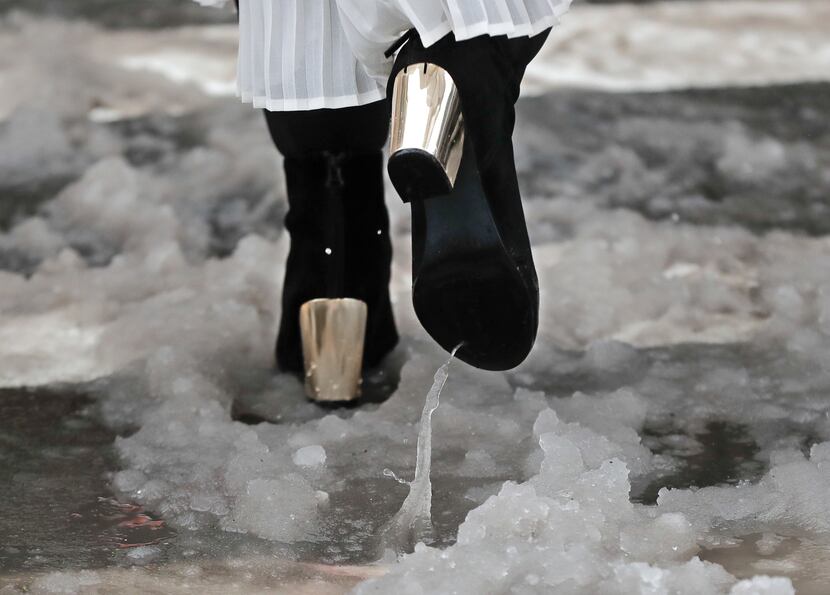 A woman walks through slush as she crosses the street on her way to a fashion show during...