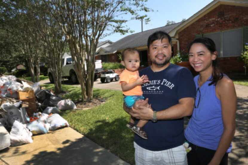 Troy y Catherine Pham, junto a su niño de 13 meses, fuera de su casa afectada por las...