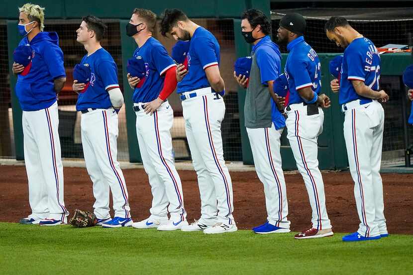 Texas Rangers players stand for the national anthem before exhibition game against the...