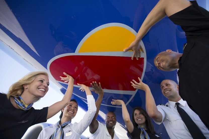  Southwest employees with one of the company's planes that features its new heart logo....