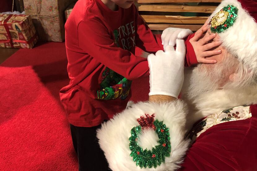 Matthew Foster, 6, of Watauga, who is blind, asked to feel Santa James Langley's twinkling...