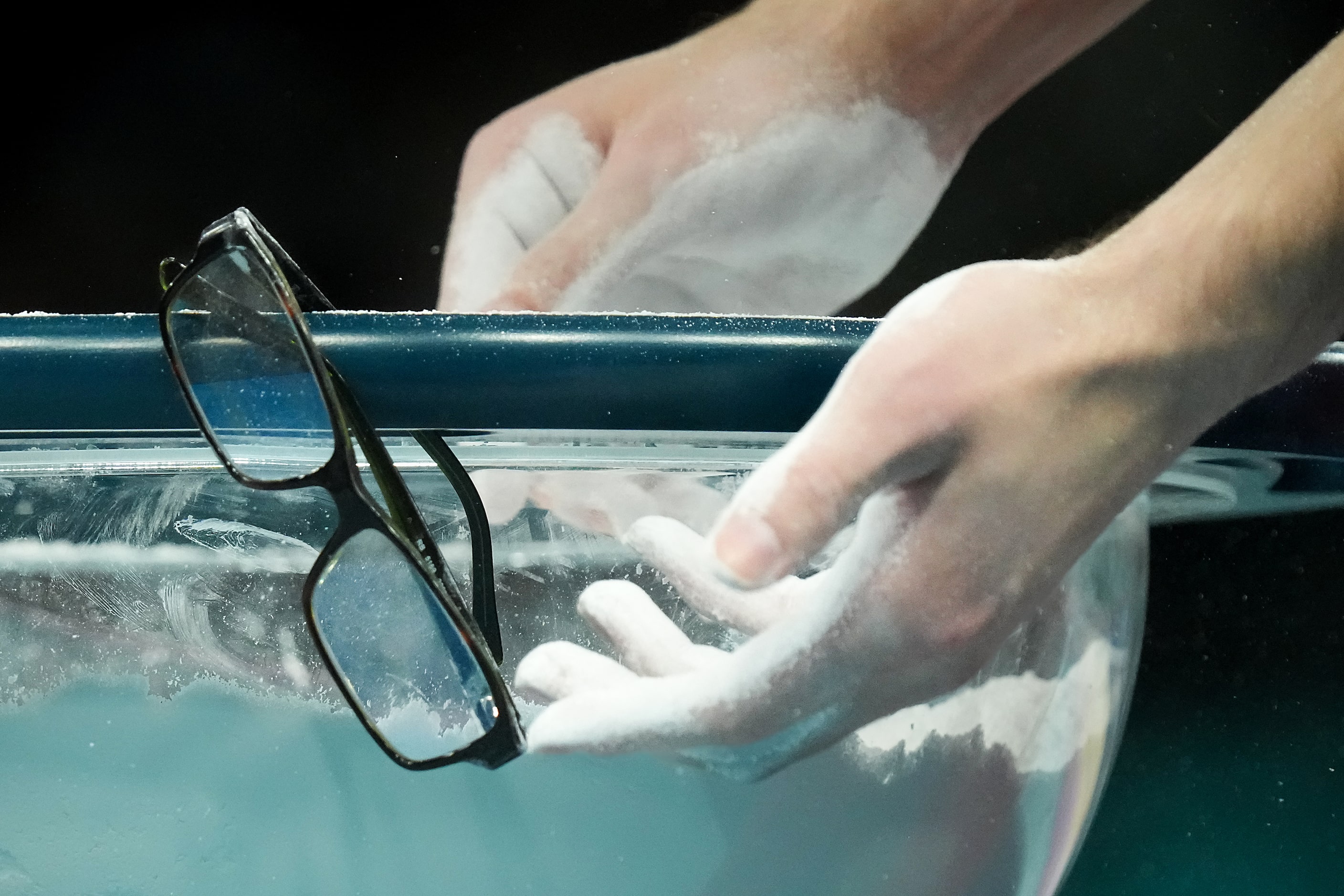 Stephen Nedoroscik of the United States hangs his glasses on the side of the chalk box...