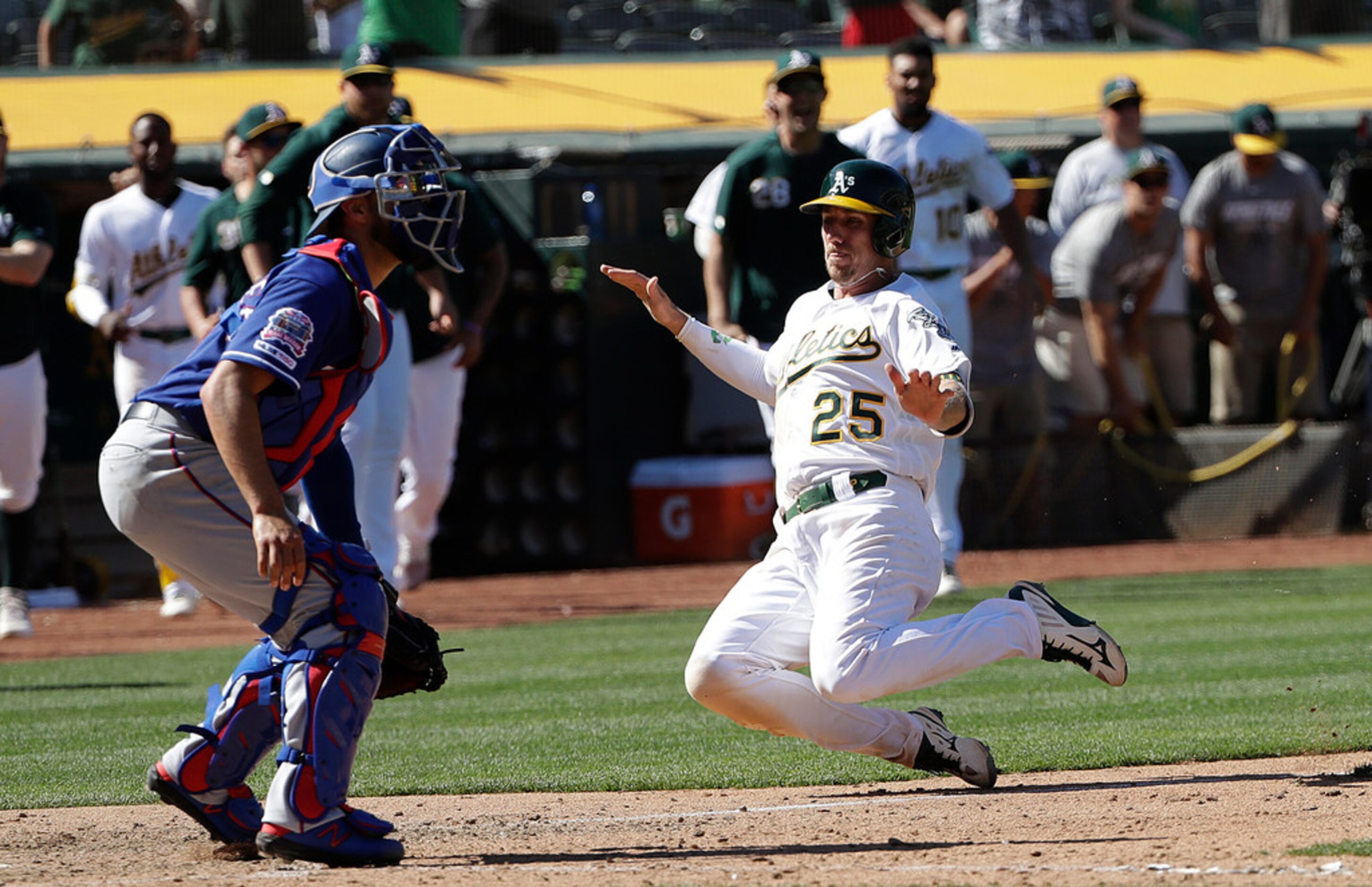 Oakland Athletics' Stephen Piscotty (25) slides in to home to score the winning run as Texas...