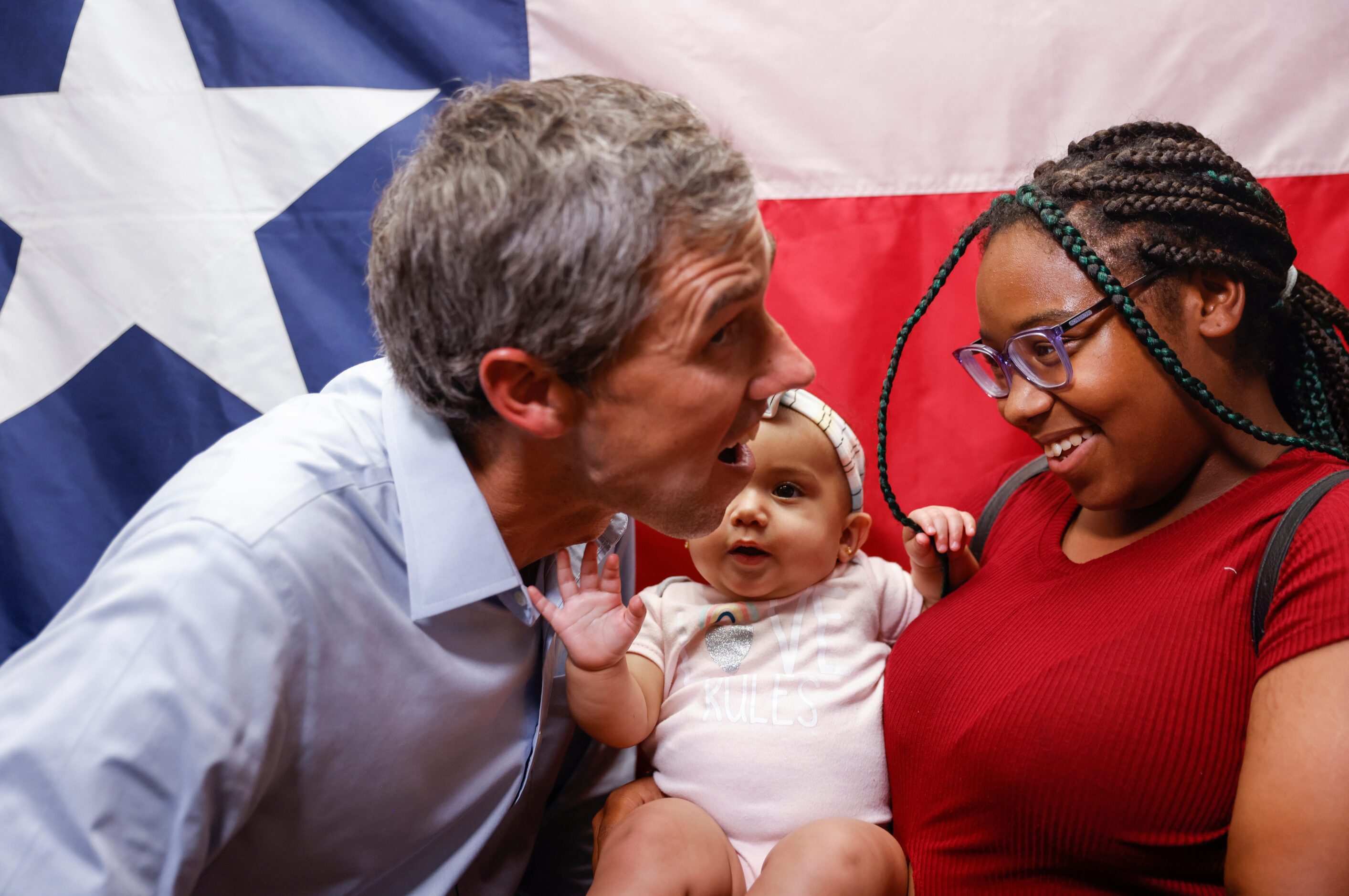 Carried by her cousin Nyla Horn, right, Eight-month-old Lyric Polk, center, gestures to...