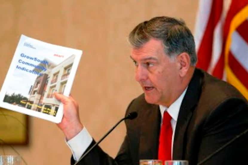 
Mayor Mike Rawlings holds up a draft for Grow South Community Indicatiors draft during his...