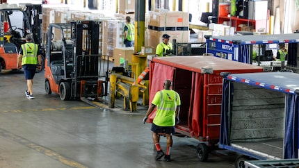 American Airlines workers move cargo around a warehouse as they prepare it for upcoming...