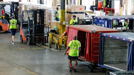 American Airlines workers move cargo around a warehouse as they prepare it for upcoming...