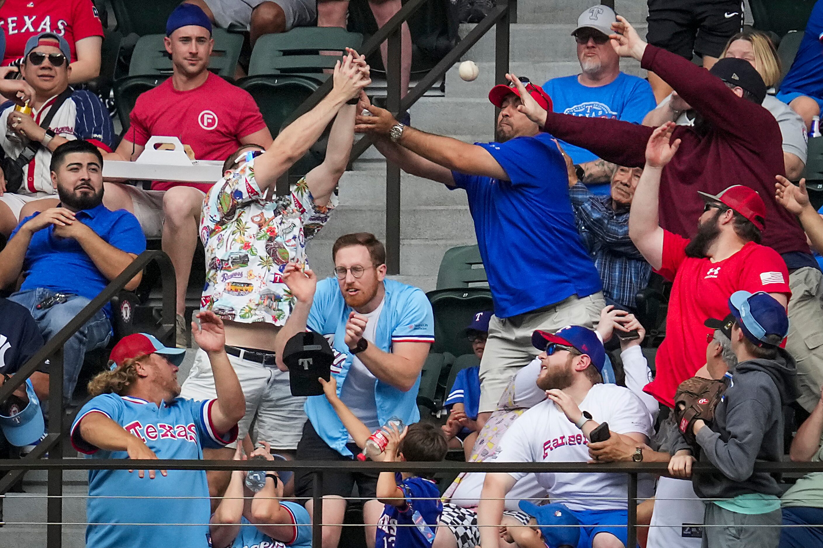 Fans reach for the ball on a two-run home run by Texas Rangers designated hitter Corey...