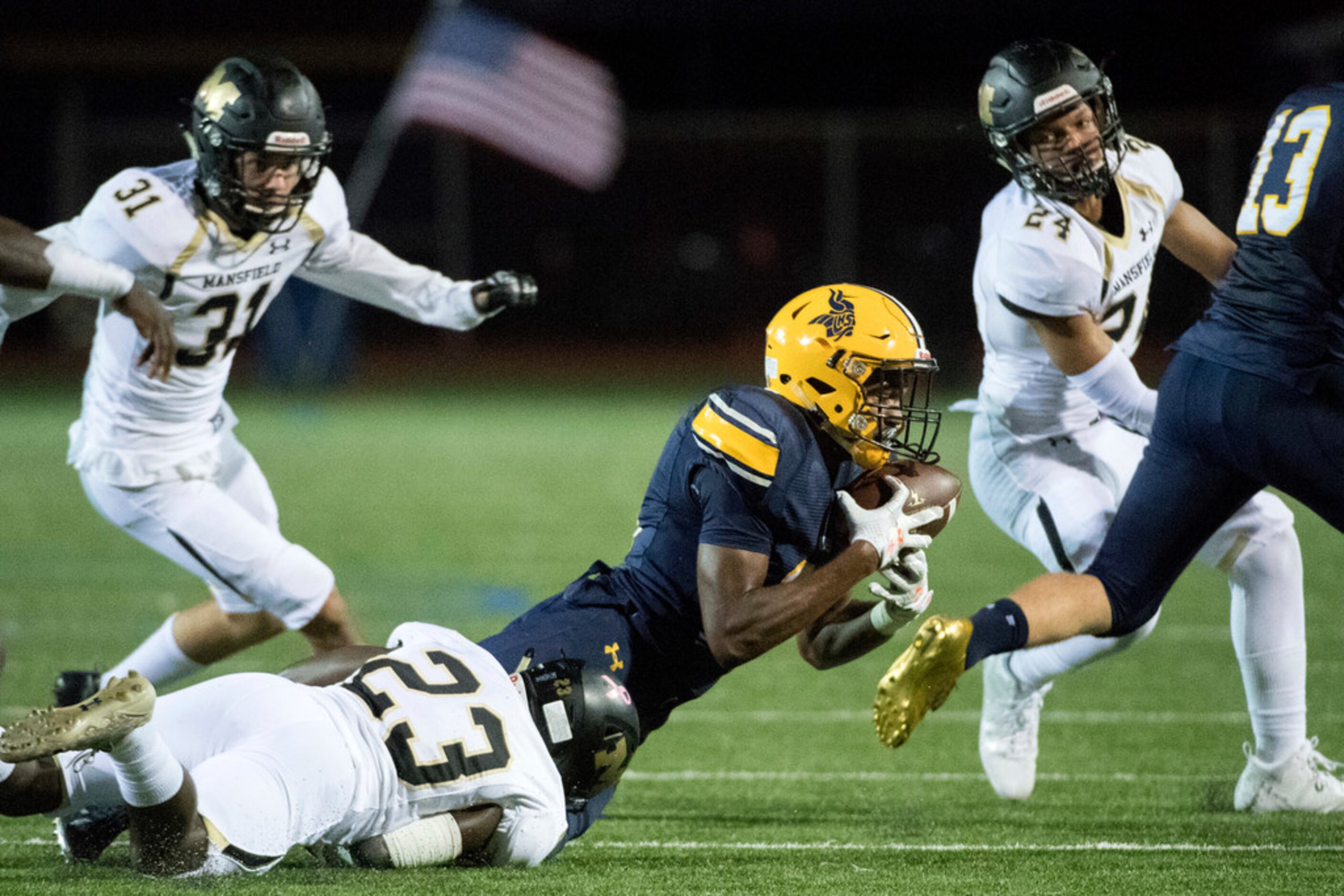 Arlington Lamar sophomore kick returner James Douglas (18) clings to the football as he is...