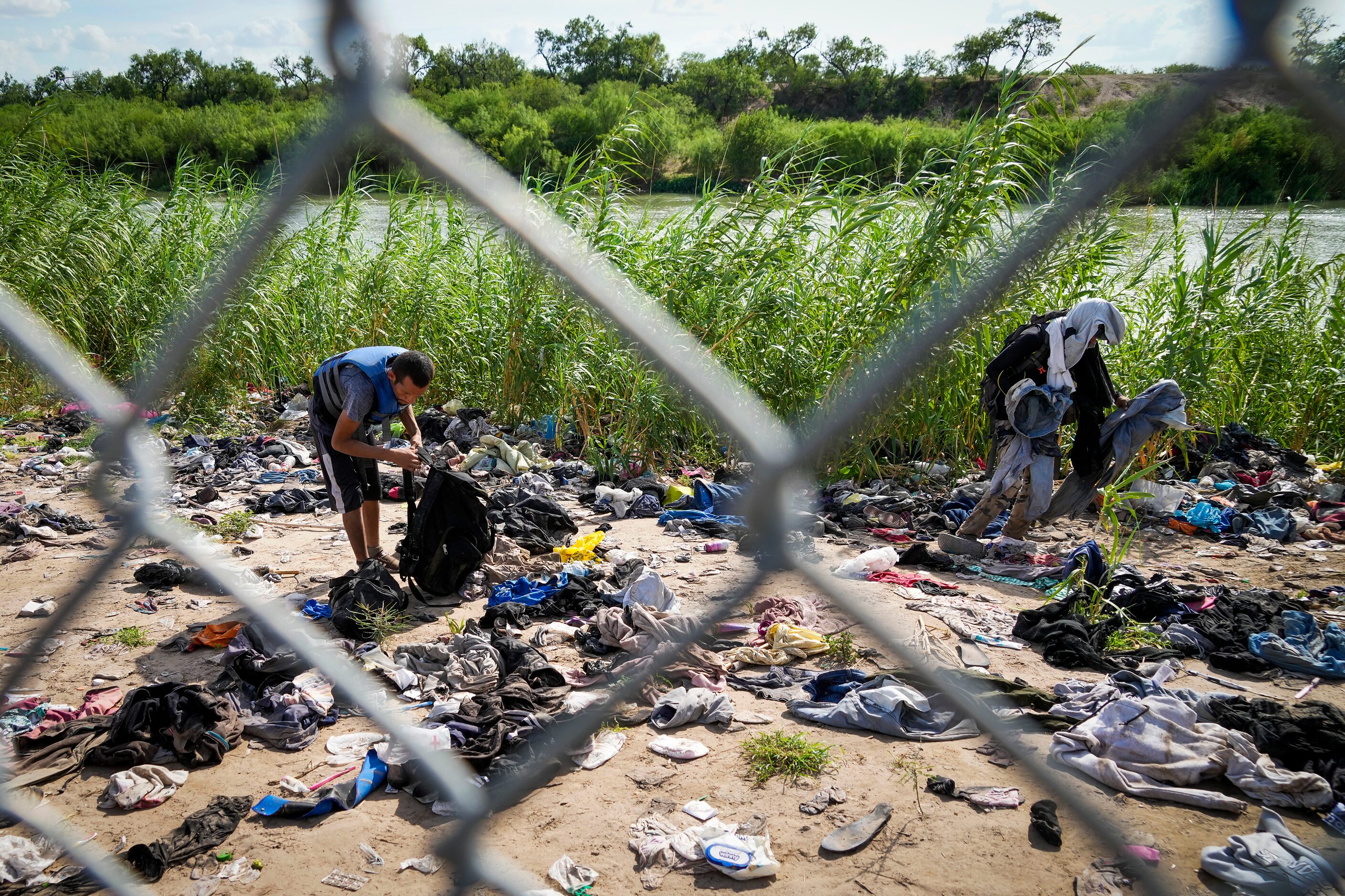 Men pick through abandoned clothing and other items strewn between the banks of the Rio...