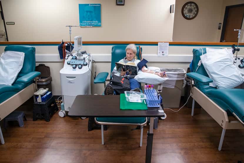 Barbara Wells donates blood between two empty donation stations at the Carter BloodCare...