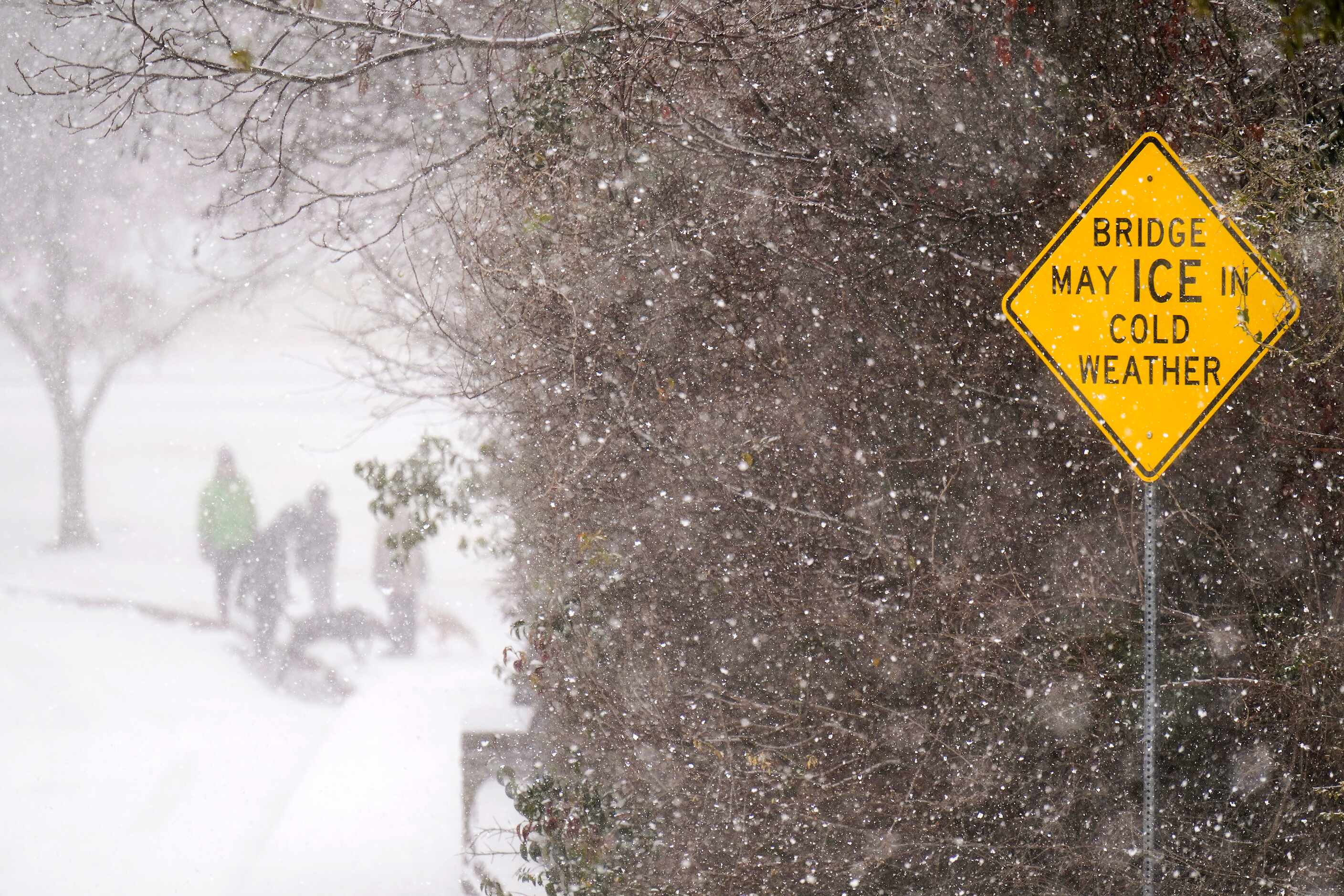 People walks across a bridge at in Prairie Creek Park as a winter storm moves into...