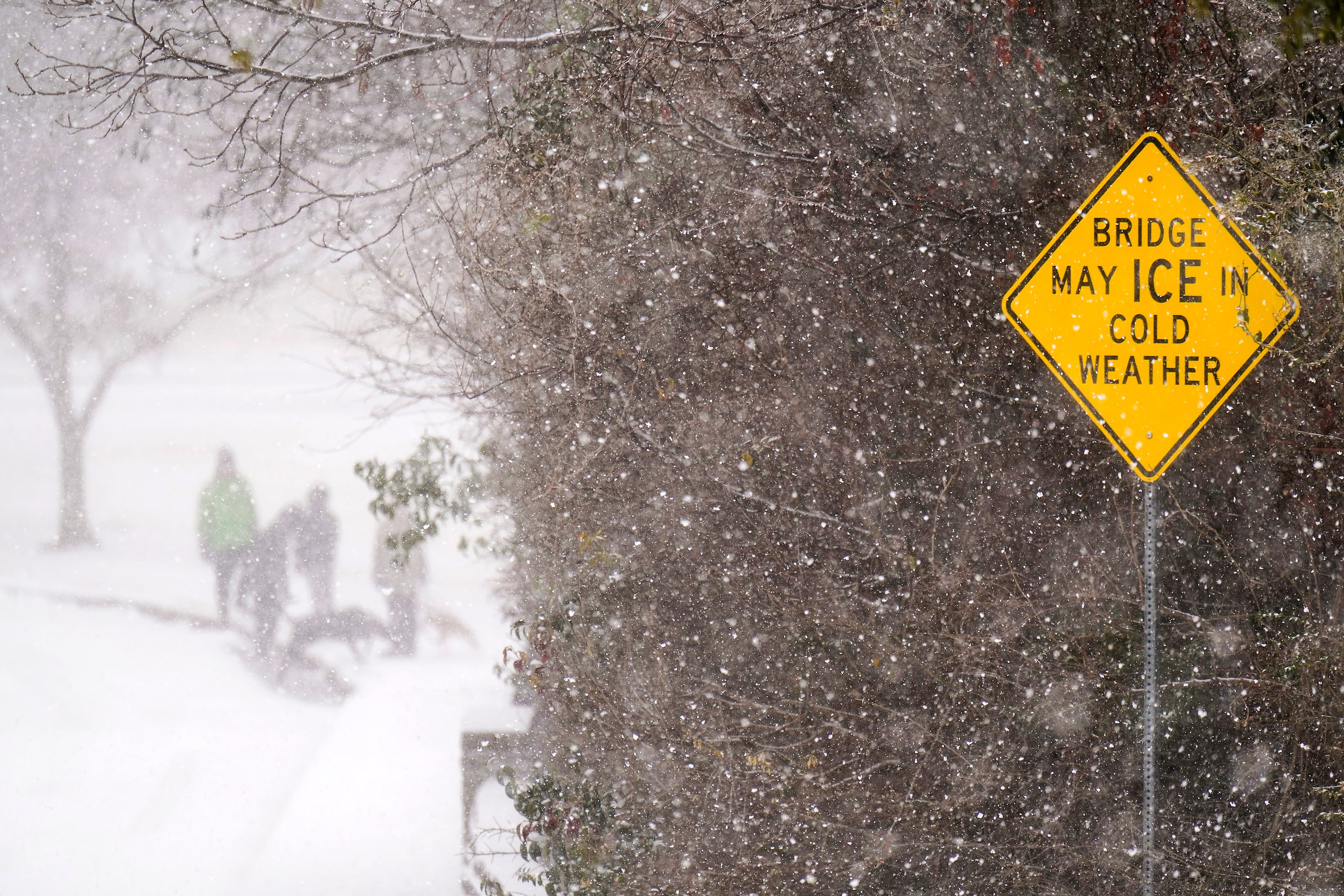 People walks across a bridge at in Prairie Creek Park as a winter storm moves into...