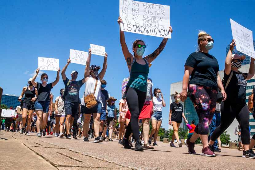 Protesters march in a silent demonstration at Dallas City Hall to denounce police brutality...