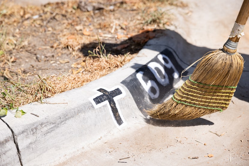 Francisco Villegas sweeps the driveway in front of the cross curb stencil honoring his son,...