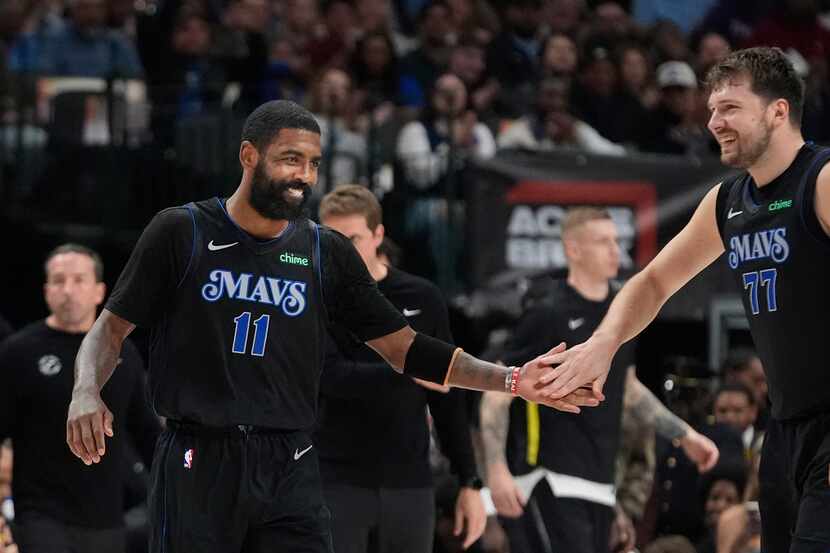 Dallas Mavericks teammates Kyrie Irving (11) and Luka Doncic (77) reach out to each other at...