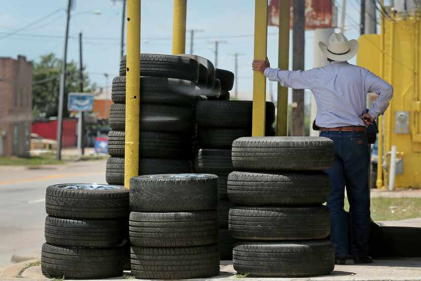 A tire shop employee awaits customers on Singleton Boulevard in West Dallas.