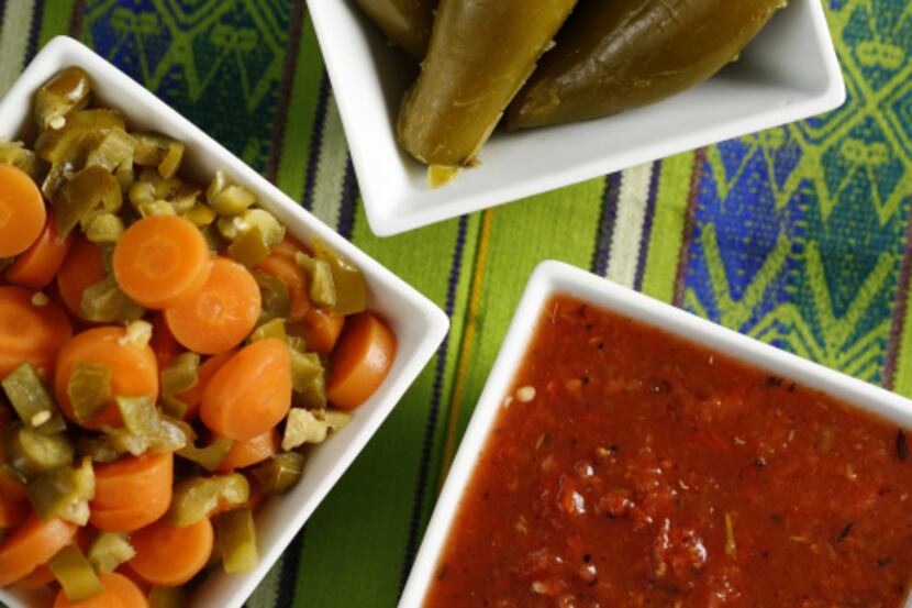 Simple Salsa Tatemada, canned pickled carrots in escabeche, and pickled jalapenos are some...