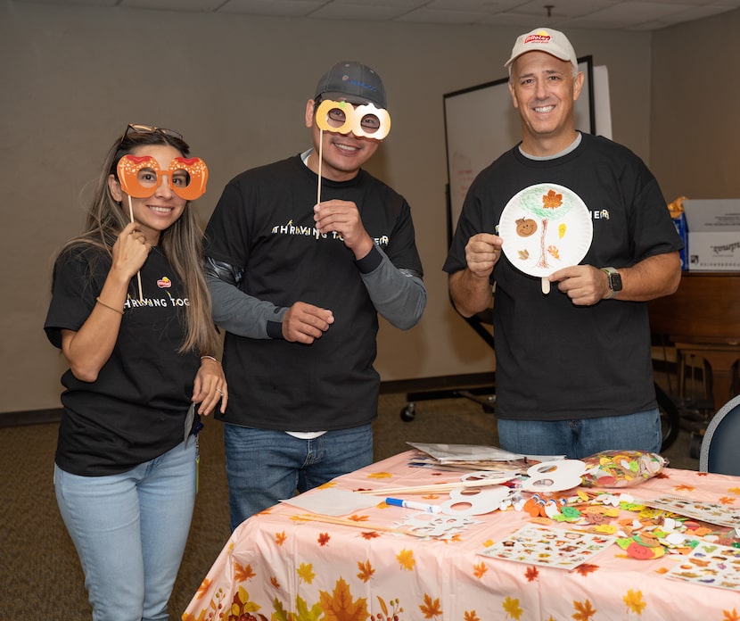 Frito-Lay employees hosting a fall fair for kids while holding up fall decorations.