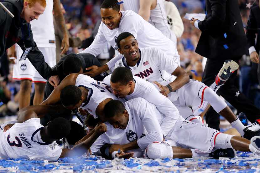 Teammates pile on top of Connecticut Huskies center Amida Brimah (35), who was making snow...