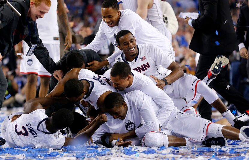 Teammates pile on top of Connecticut Huskies center Amida Brimah (35), who was making snow...