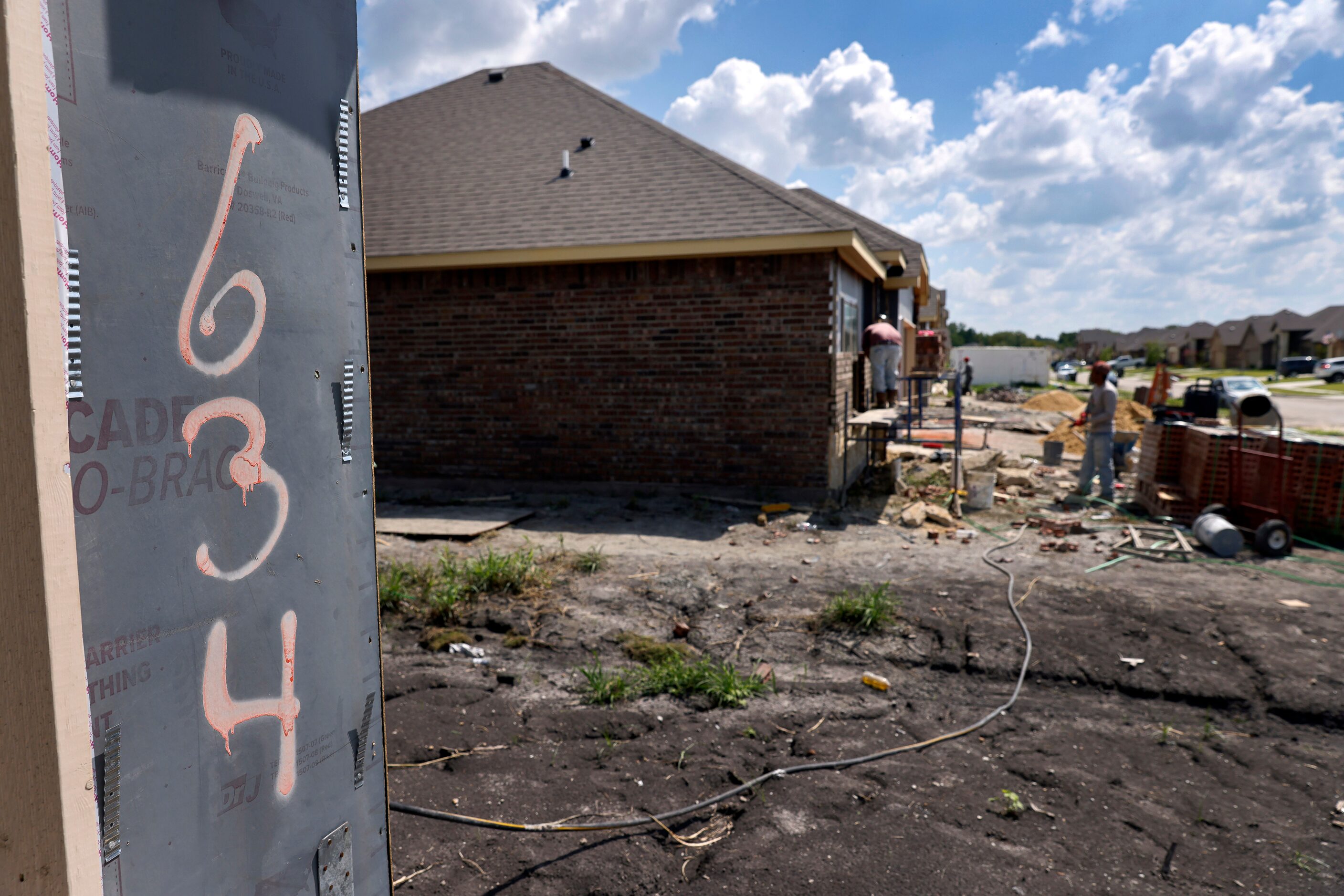 Construction workers build single-family homes in the new River Ridge Community. There are...