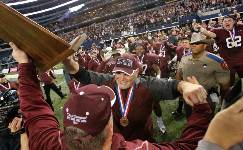 Ennis coach Jack Alvarez receives the state championship trophy after the Lions' 38-35 win...