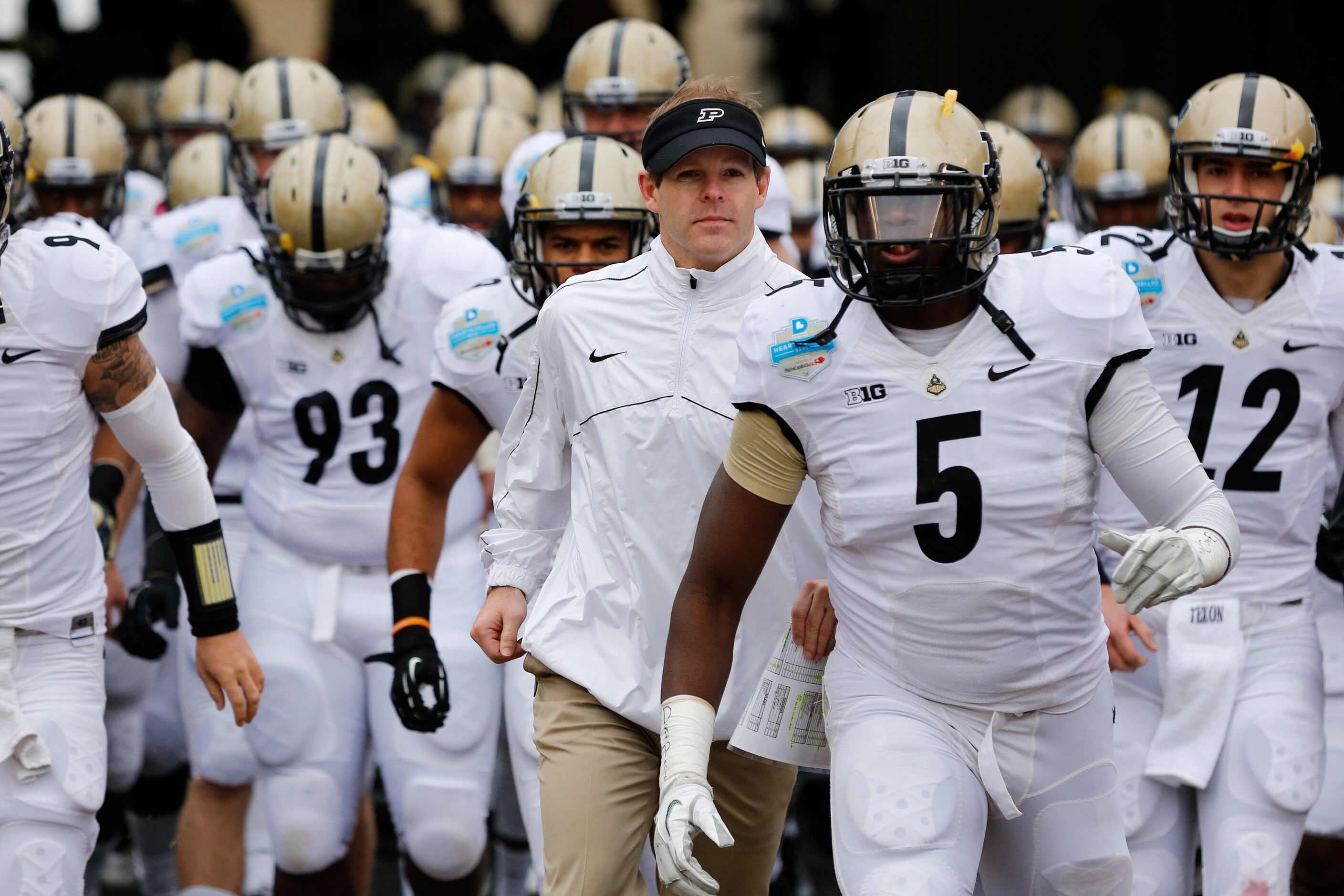 Purdue's interim head coach Patrick Higgins runs onto the field with his team during the...