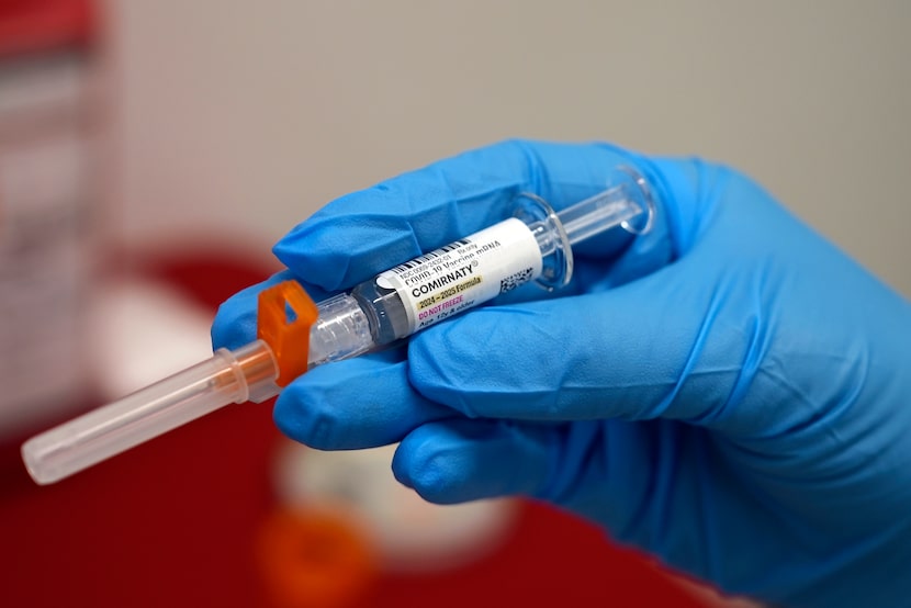 A pharmacist holds a COVID-19 vaccine at a pharmacy in New York, on Sept. 24, 2024. (AP...