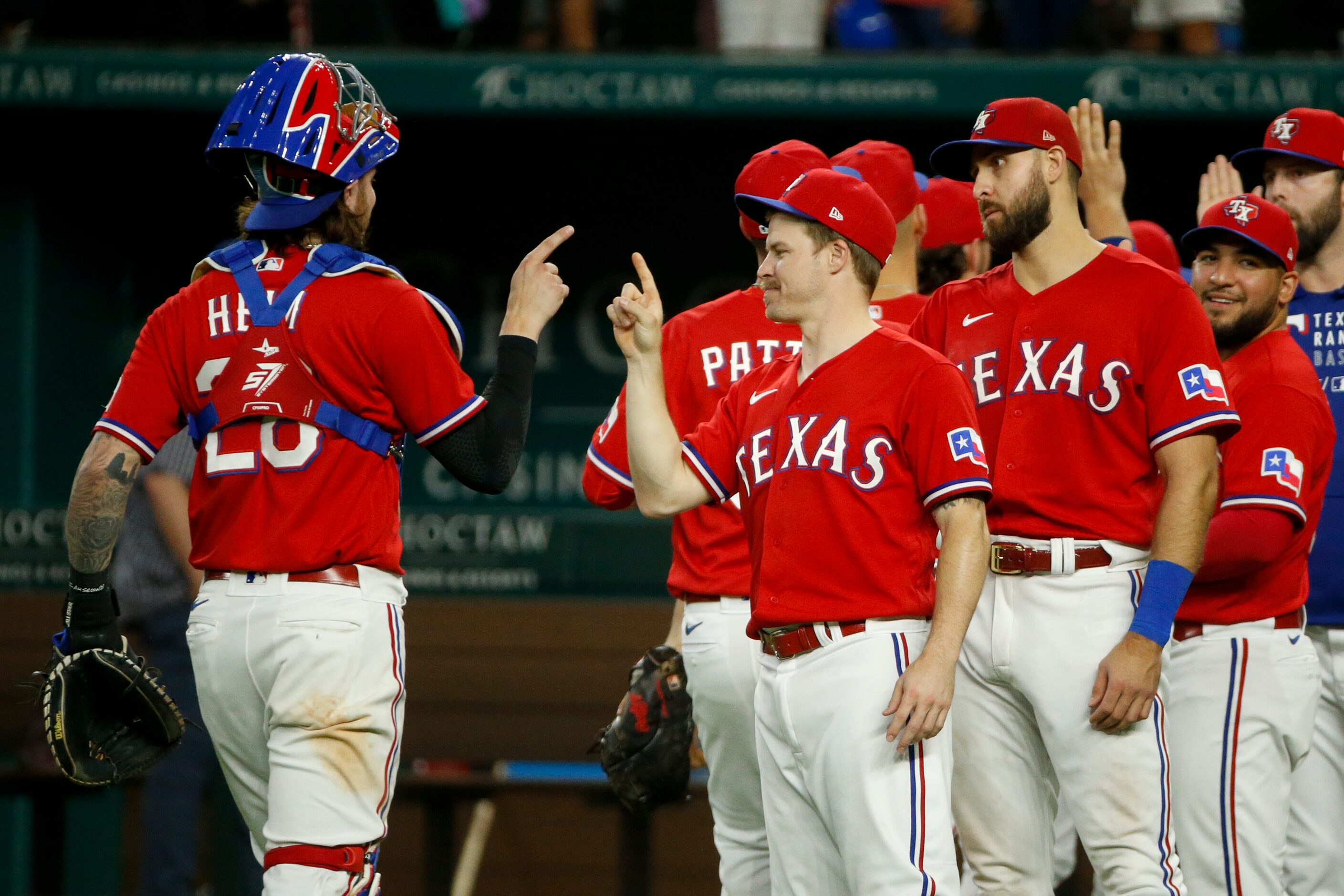 Texas Rangers catcher Jonah Heim (28) and second baseman Brock Holt (16) tap fingers after a...