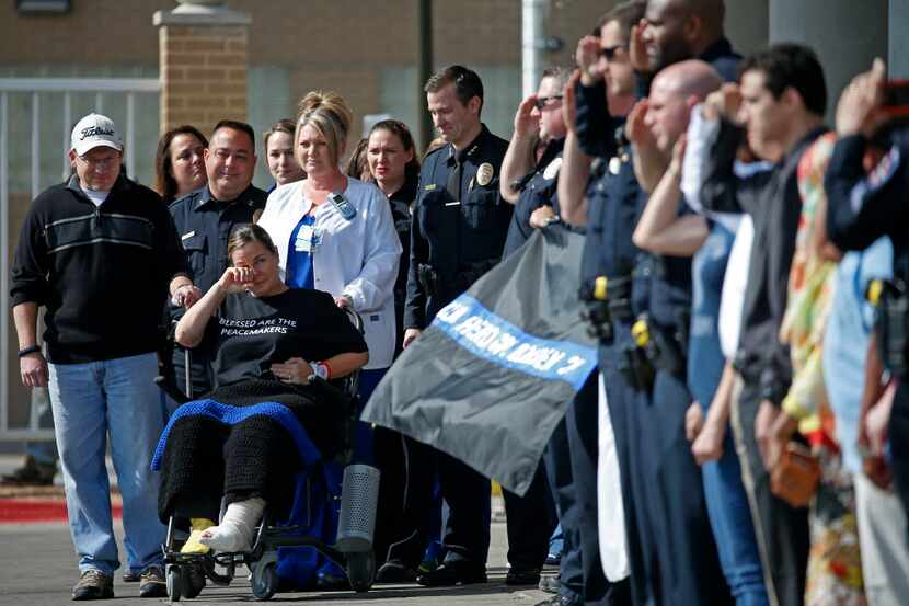 Arlington police officer Cpl. Elise Bowden (in a wheelchair) wipes tears away as police...
