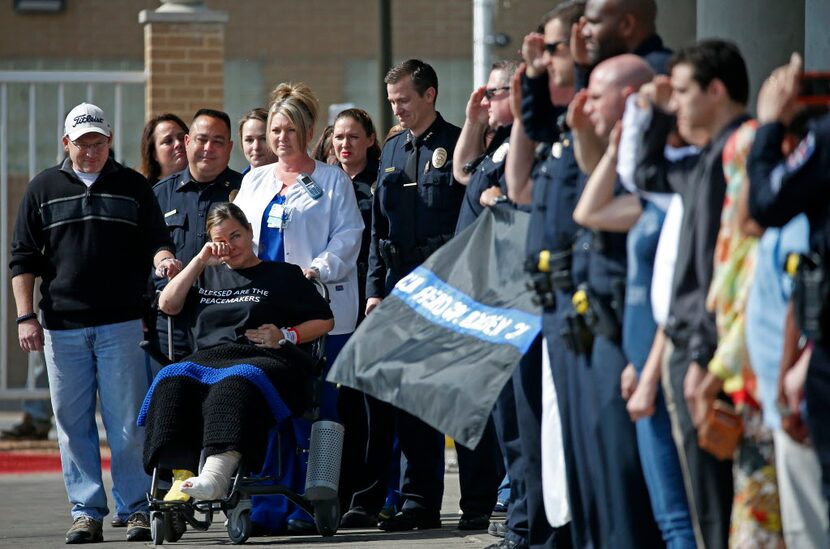 Arlington police officer Cpl. Elise Bowden (in a wheelchair) wipes tears away as police...