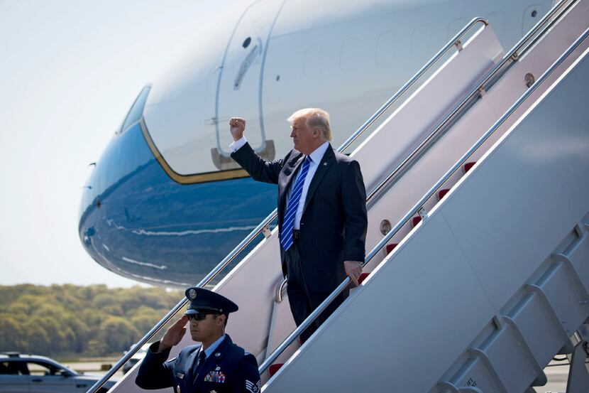 President Donald Trump raises a fist as he leaves Air Force One Wednesday morning after...
