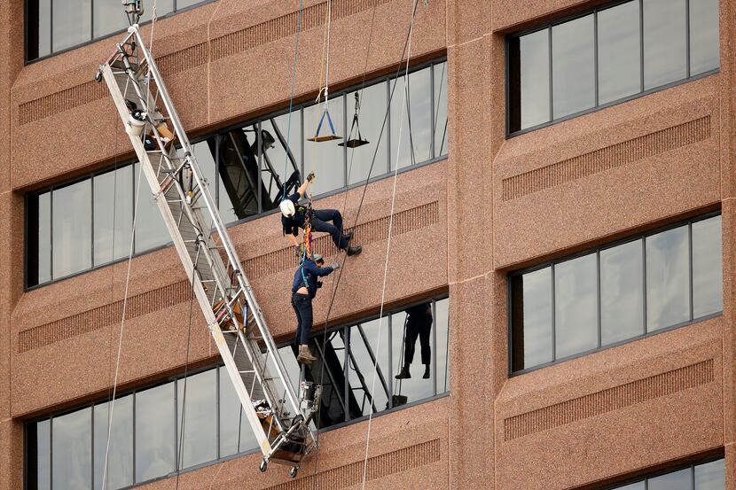 Dallas Fire-Rescue Urban Search and Rescue member Jonathan Formby (top) lowers one of two...