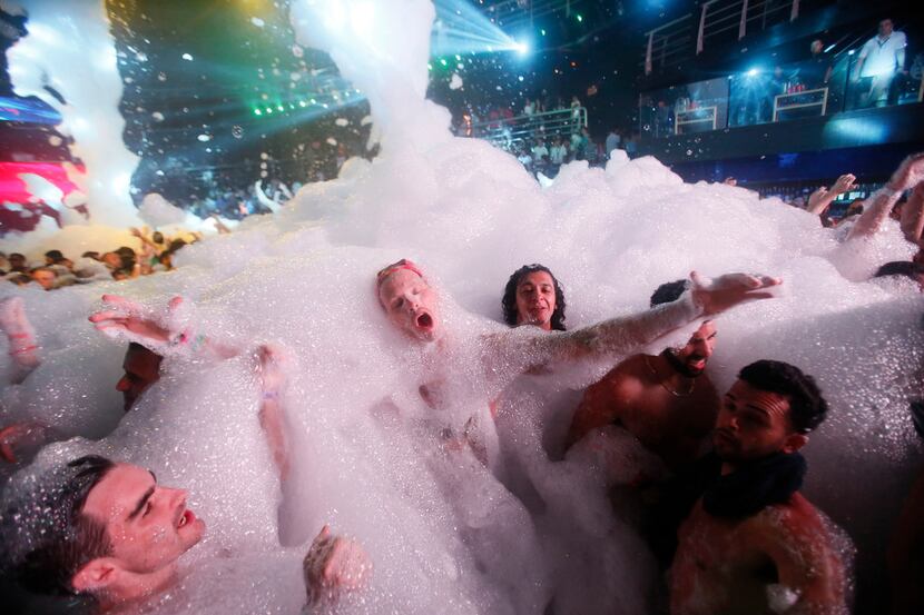 Partygoers dance in foam at The City nightclub in the Caribbean resort city of Cancun,...