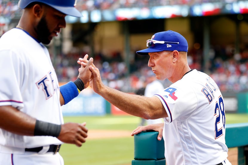 Texas Rangers manager Jeff Banister (28) gives shortstop Elvis Andrus (1) a high five after...