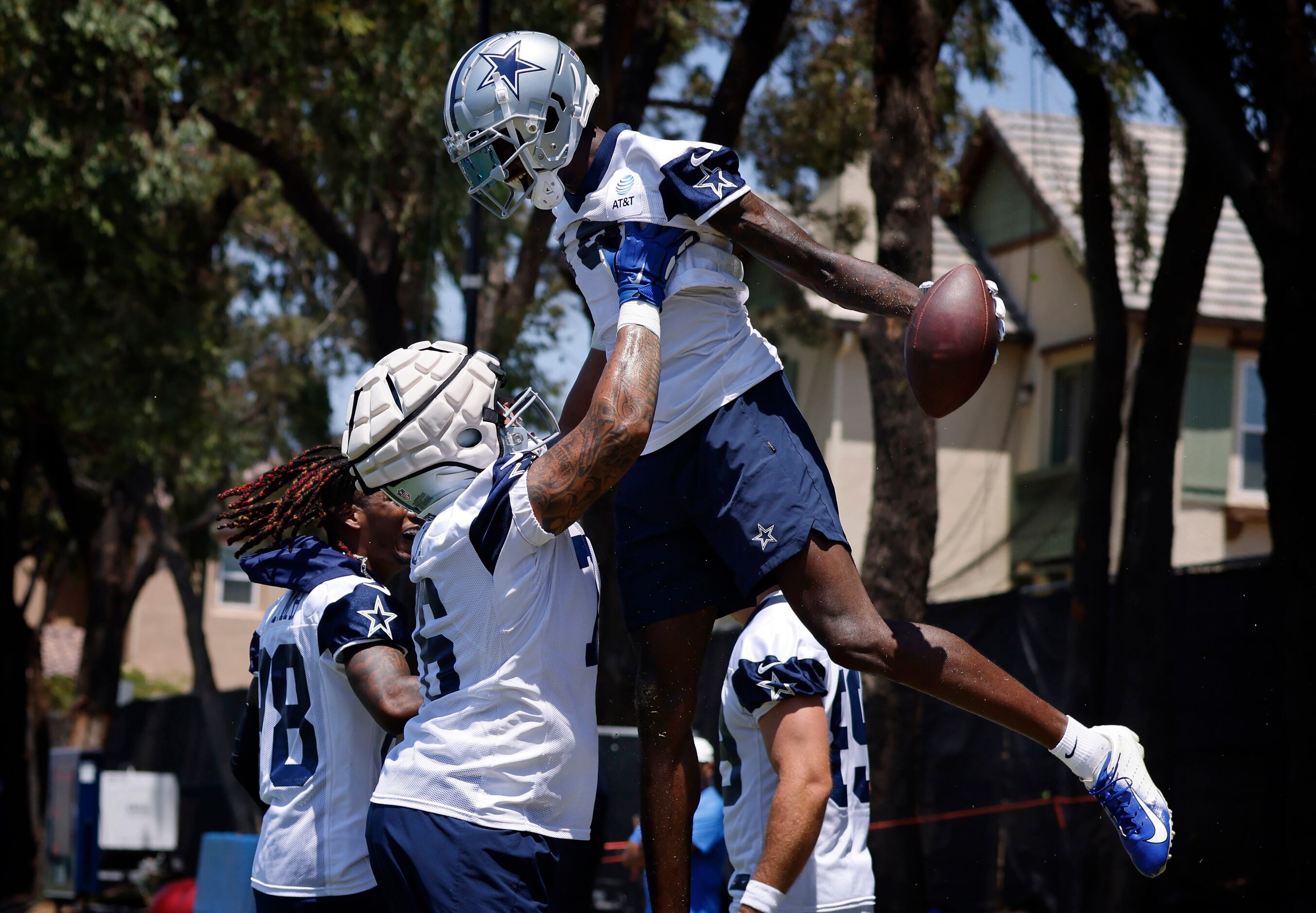 Dallas Cowboys offensive tackle Aviante Collins (76) hoists wide receiver T.J. Vasher (16)...