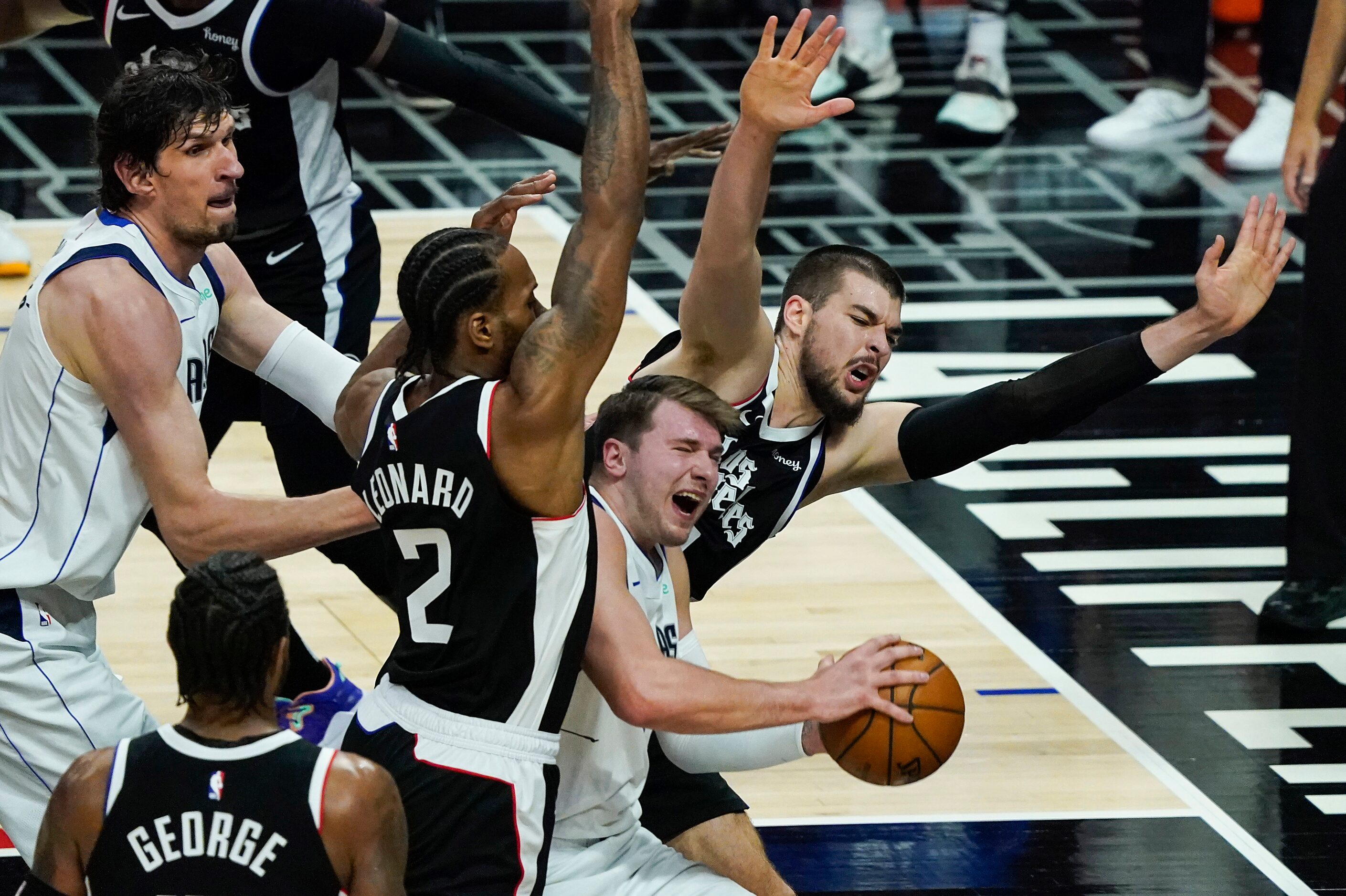 Dallas Mavericks guard Luka Doncic (77) is fouled as he tries to drive between LA Clippers...