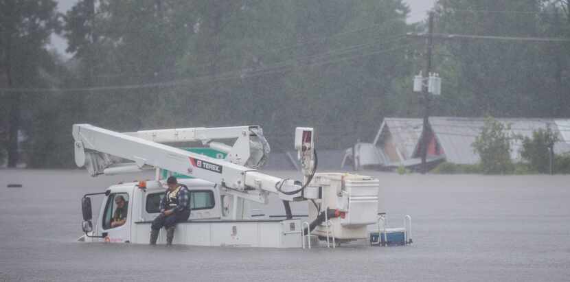 Men wait on a utility vehicle that was stuck on Highway 96 in flood waters from Hurricane...